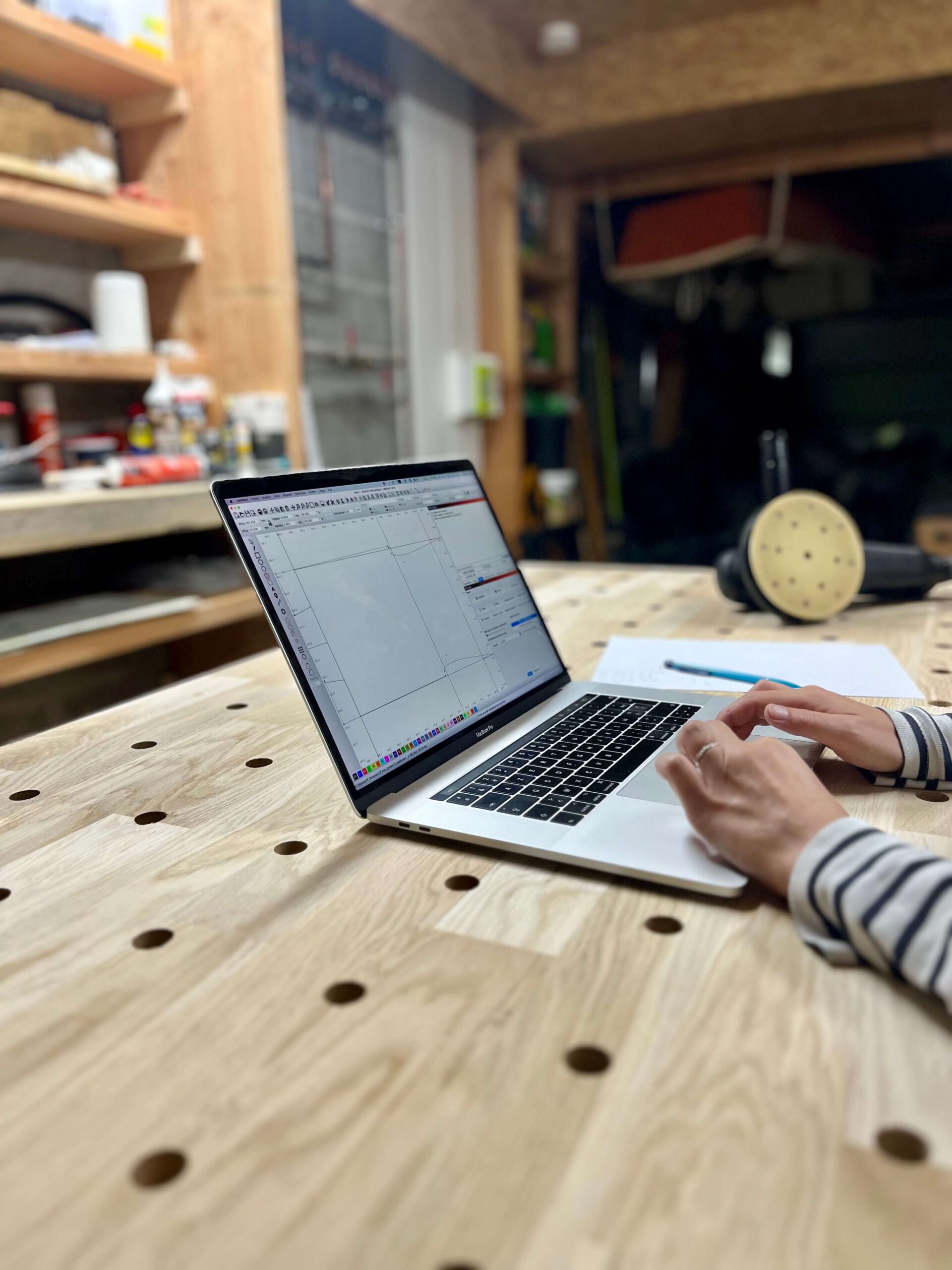 Personne travaillant sur un ordinateur posé sur un établi dans un atelier