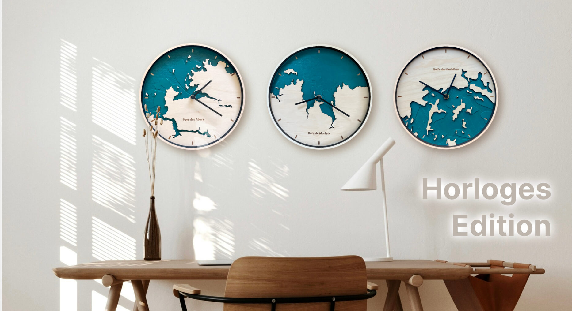 Trois horloges Wenn O'Clock Edition au dessus d'un bureau en bois